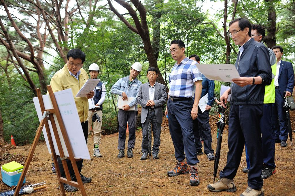 봉황산 나래숲 공원조성 현장점검중 직원들에게 브리핑을 받고 있는 모습