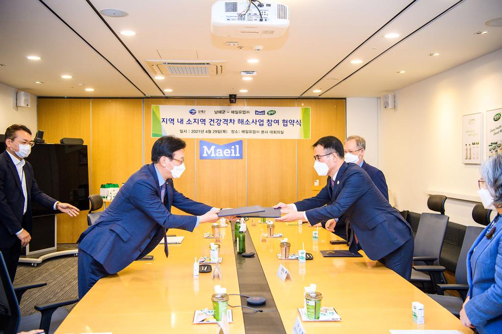 서울 매일유업 본사에서 진행된 지역내 소지역 건강격차 해소사업 영양식품제공 및 연구협력 협약서를 싸인후 서로 전달하고 있다